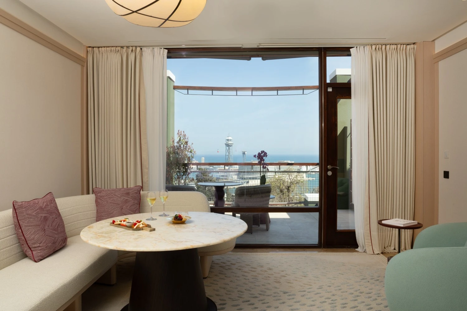 Salón de la Junior Suite con grandes ventanales y vistas panorámicas al mar Mediterráneo.